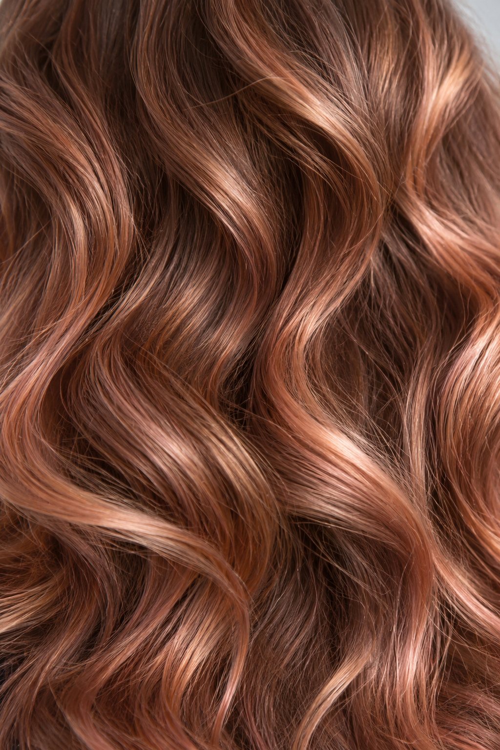 Détail de cheveux ondulés aux reflets cuivrés et rosés